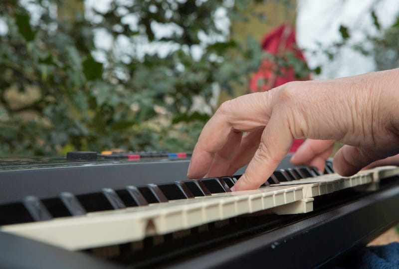 Hand speelt piano buiten in de natuur, beeld voor muziektherapie volwassenen